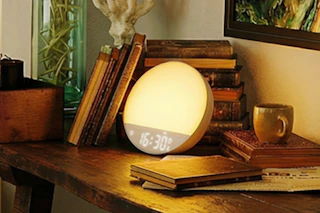 sunrise alarm clock by books on desk