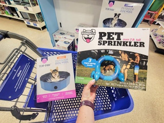 hand holding a pet sprinkler over a cart with a pet pool in it