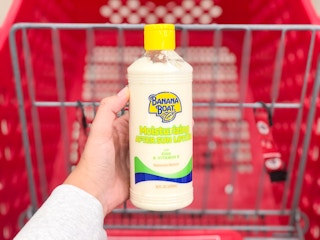 hand holding bottle of Banana Boat after sun lotion in front of a shopping cart at Target