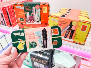 Someone holding a Benefit Merry Mini Mail Ulta gift set in front of a shelf at Target