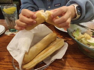 woman breaking open an olive garden breadstick