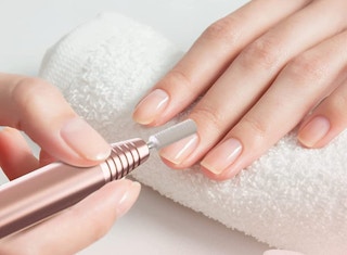 a person shaping their nails with a nail drill