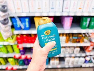 a hand holding a bottle of shampoo in a store aisle