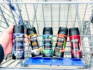 hand holding a bottle of axe body spray with four in cart