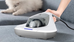 a person using a mattress vacuum on a couch