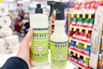 person holding mrs meyers dish soap by mrs meyers cleaning spray