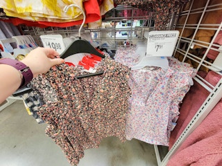 hand holding a black printed ladies top near a white printed top