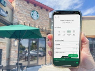a person holding a cellphone with the starbucks app with honey citrus mint drink order on screen