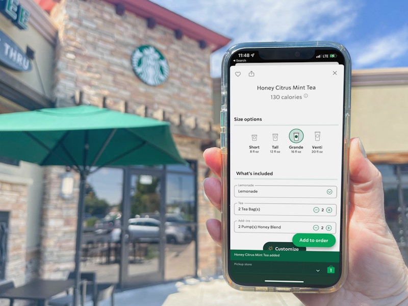 a person holding a cellphone with the starbucks app with honey citrus mint drink order on screen