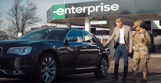 An Enterprise employee showing a vehicle to someone in military uniform