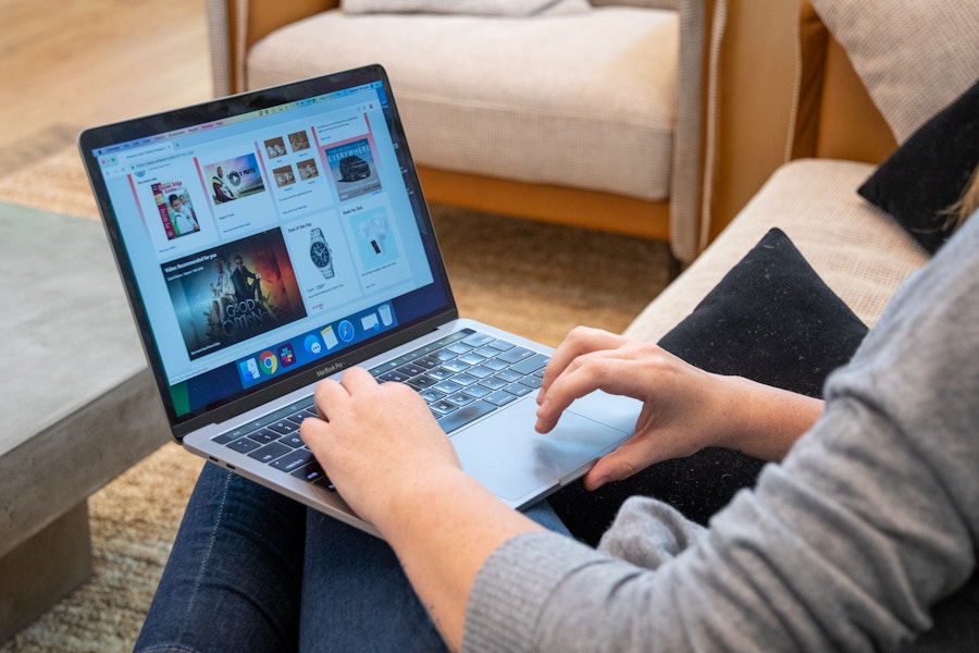 A woman sitting with a laptop on her lap, browsing amazon.com