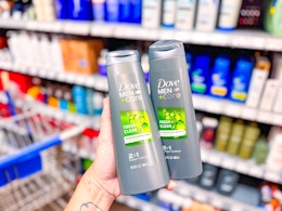 hand holding two bottles of dove men care 2-in-1 shampoo in walmart aisle