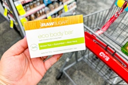 person holding raw sugar bar soap over a cart