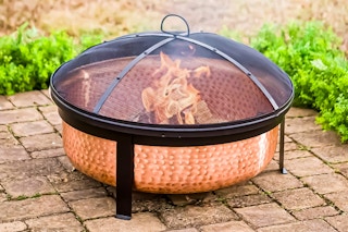 Lifestyle image of the Better Homes & Gardens Copper Fire Pit in outdoor setting