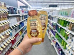 hand holding garnier whole blends shampoo in walgreens