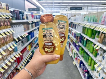 hand holding garnier whole blends shampoo in walgreens