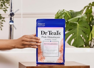 a hand holding a bag of epsom salt soak