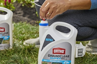 a person using a bottle of weed killer on grass