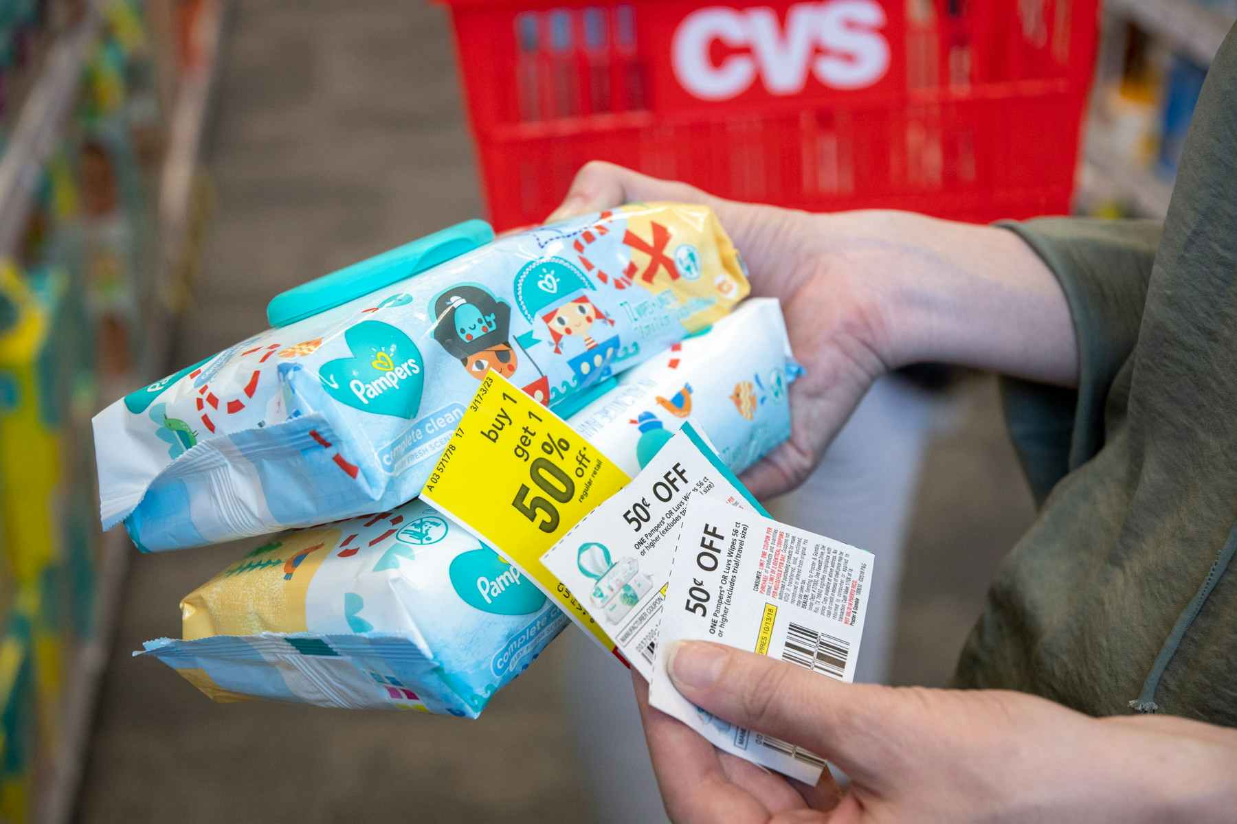 someone holding coupons and baby wipes next to cvs basket