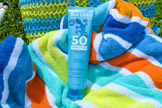 Blue lizard sensitive sunscreen on beach towel