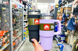 person holding 2 ozark tumblers in an aisle