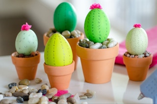Some eggs painted like cactuses sitting in tiny pots