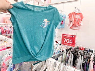 someone holding a teal kids shirt with a mermaid on it