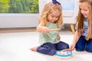 Lifestyle image of a little girl playing with the Melissa & Doug Music Maker toy with an older little girl