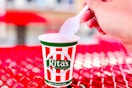 A hand holding a spoon scooping Italian ice from a Rita's cup.