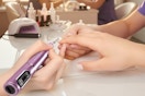 a woman using a cordless nail drill in a salon