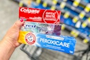 person holding 3 toothpastes over a cart