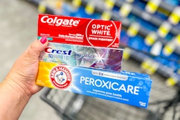 person holding 3 toothpastes over a cart