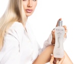 a woman holding a bottle of hair treatment
