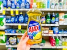 person holding an ajax dish soap in front of a shelf