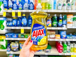 person holding an ajax dish soap in front of a shelf