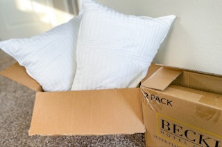 two pillows in an open box next to a closed box on the floor
