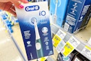 person holding an oral-b electric toothbrush by the display