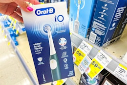 person holding an oral-b electric toothbrush by the display