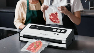two people sealing steaks in vacuum-sealed bags