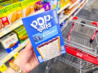 person holding a box of pop tarts over a cvs cart