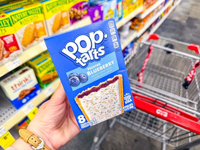 person holding a box of pop tarts over a cvs cart