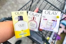 person holding olay moisturizer and super serum over a cart