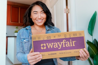 a woman holding a wayfair box in her doorway