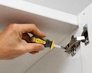 a person using a mini screwdriver on cabinet