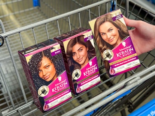 hand holding box of schwarzkopf keratin root with two more in walmart cart