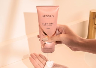 a pink tube of hair heat protectant being squeezed into a hand