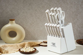 A white knife set in a white block with a built-in sharpener sits on the right side of a counter. On the left is a round bottle with a hole.