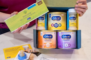 A woman holding up an Enfamil formula baby sample freebie box, showing the contents inside.