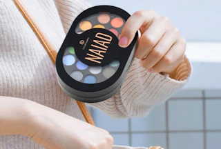 a person putting a makeup palette in their bag 