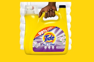 a jug of detergent in front of a stack of white towels